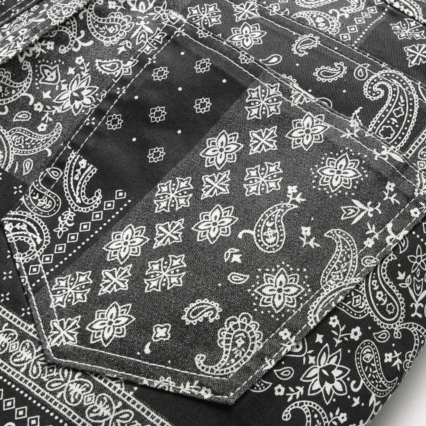 Men's relaxed-fit paisley print jeans with intricate black and white patterns, highlighting premium denim quality.