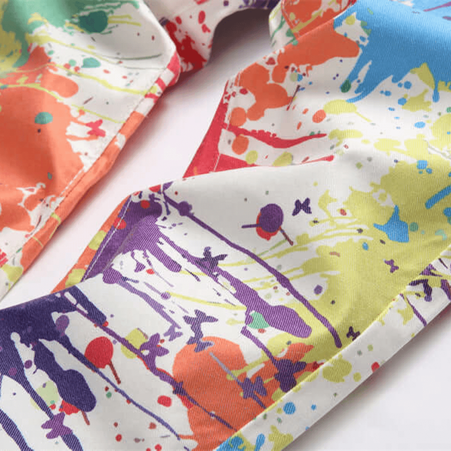 Close-up of multi-color paint splatter design on men's slim-fit jeans, showcasing premium denim fabric.
