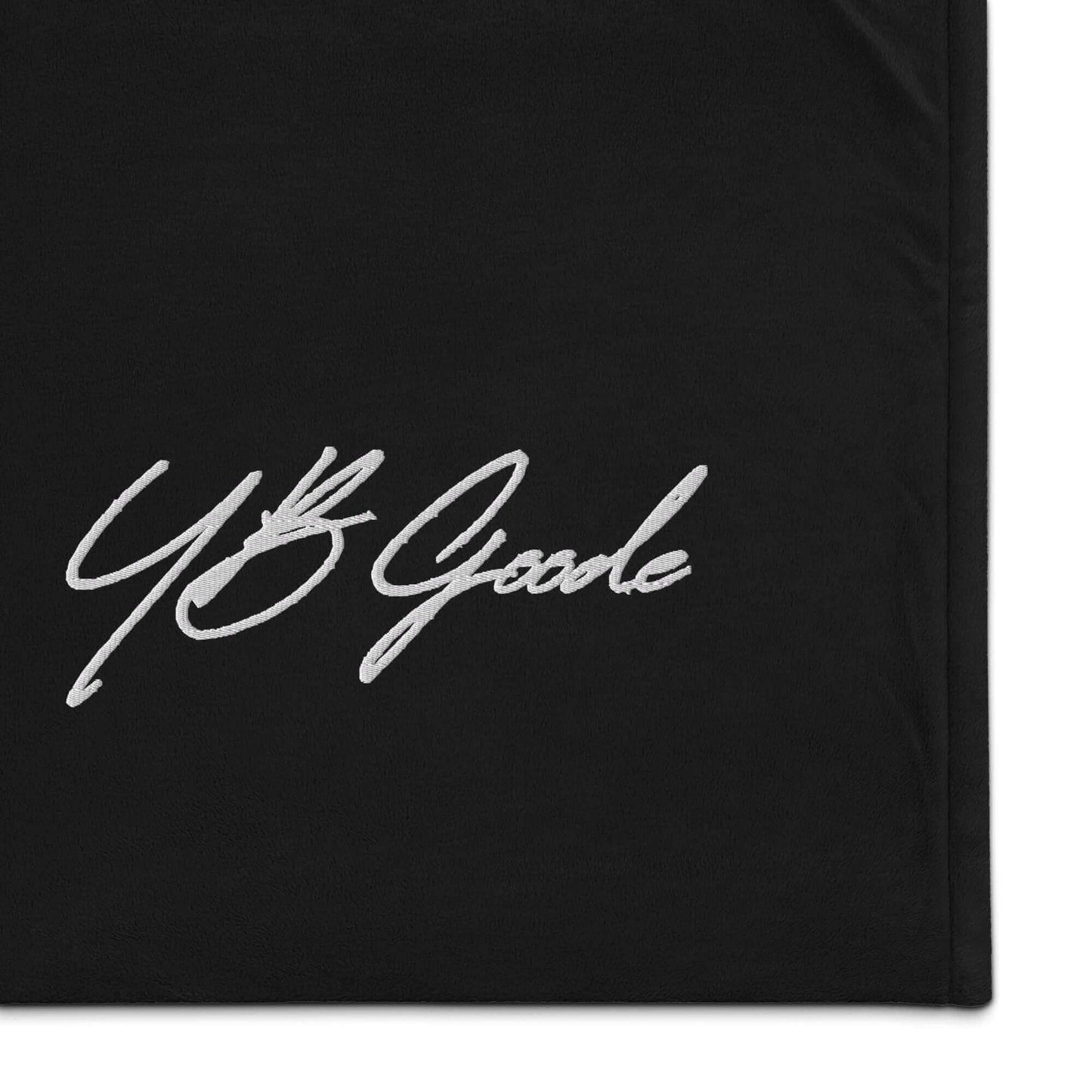 Close-up of YB Goode signature embroidered on a premium black sherpa blanket.