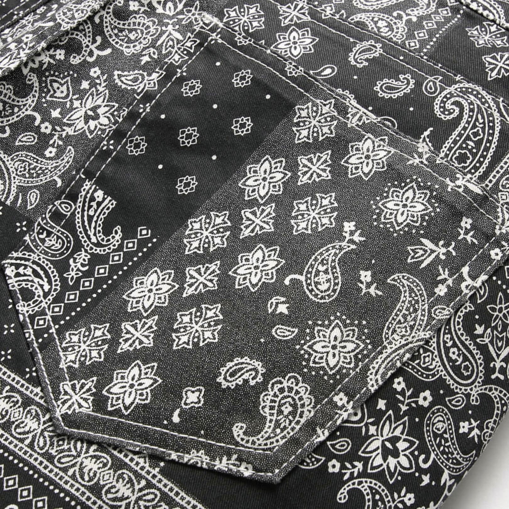 Men's relaxed-fit paisley print jeans with intricate black and white patterns, highlighting premium denim quality.