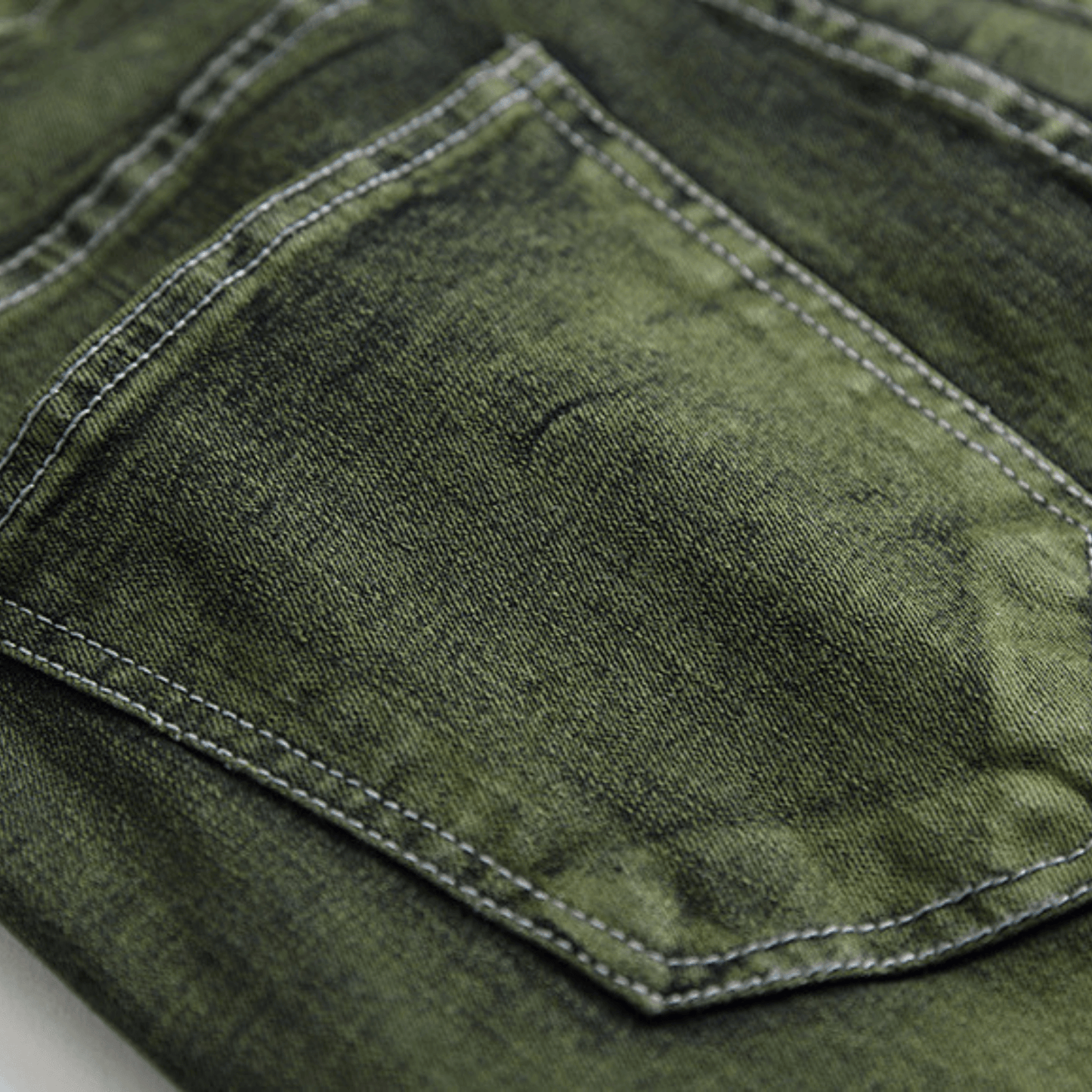 Close-up of men's slim-fit green faded designer denim jeans, showcasing premium quality and machine-washable fabric.