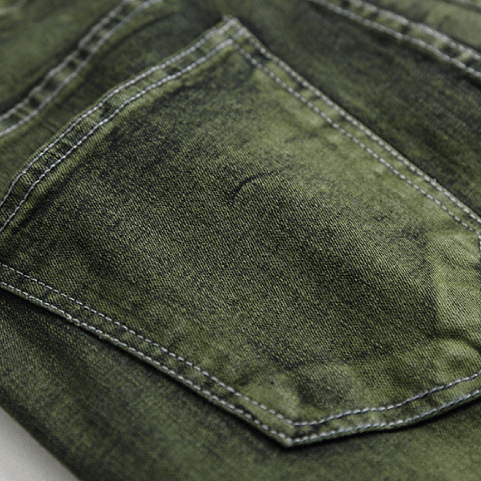 Close-up of men's slim-fit green faded designer denim jeans, showcasing premium quality and machine-washable fabric.